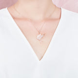 The picture shows a model wearing a 925 sterling silver, rose gold vermeil, sailfish pendant with topaz.