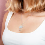 The picture shows a model wearing a 925 sterling silver, white gold vermeil, sailfish pendant with topaz.