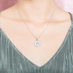 The picture shows a model wearing a small 925 sterling silver, white gold vermeil, pavé sand dollar pendant with topaz.