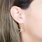 The picture shows a model wearing a 925 sterling silver pavé yellow gold vermeil sea star hook earring.