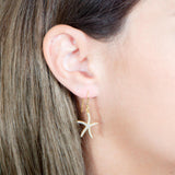 The picture shows a model wearing a 925 sterling silver pavé yellow gold vermeil sea star hook earring.