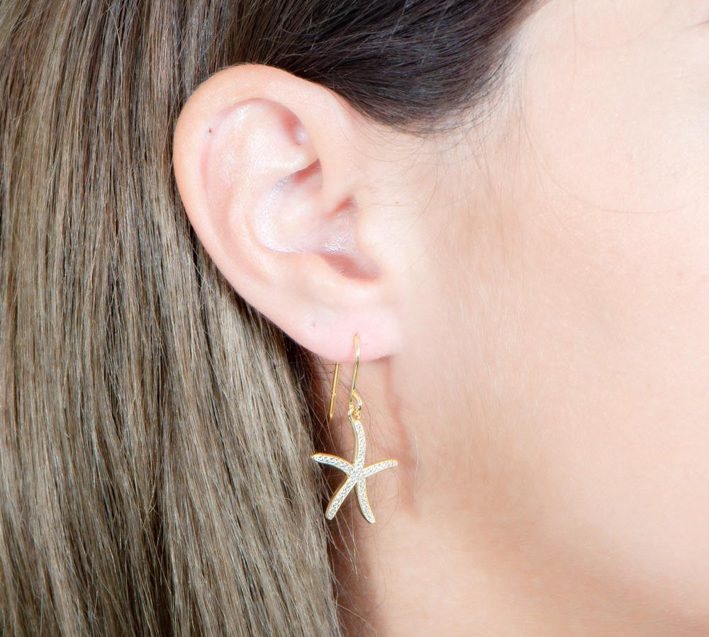 The picture shows a model wearing a 925 sterling silver pavé yellow gold vermeil sea star hook earring.