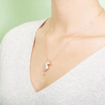 The picture shows a model wearing a 925 sterling silver, rose gold vermeil, pavé seahorse pendant with topaz.