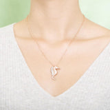 The picture shows a model wearing a 925 sterling silver, rose gold vermeil, pavé seahorse pendant with topaz.