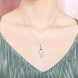 The picture shows a model wearing a 925 sterling silver, white gold vermeil, pavé seahorse pendant with topaz.