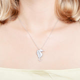 The picture shows a model wearing a 925 sterling silver, white gold vermeil, pavé seahorse pendant with topaz.