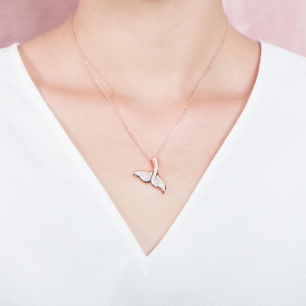 The picture shows a model wearing a 925 sterling silver, rose gold vermeil, pavé whale tail pendant with topaz.