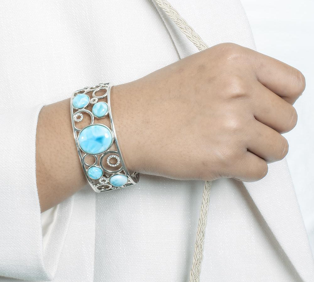 The picture shows a model wearing a 925 sterling silver bangle with five larimar gemstones and topaz.
