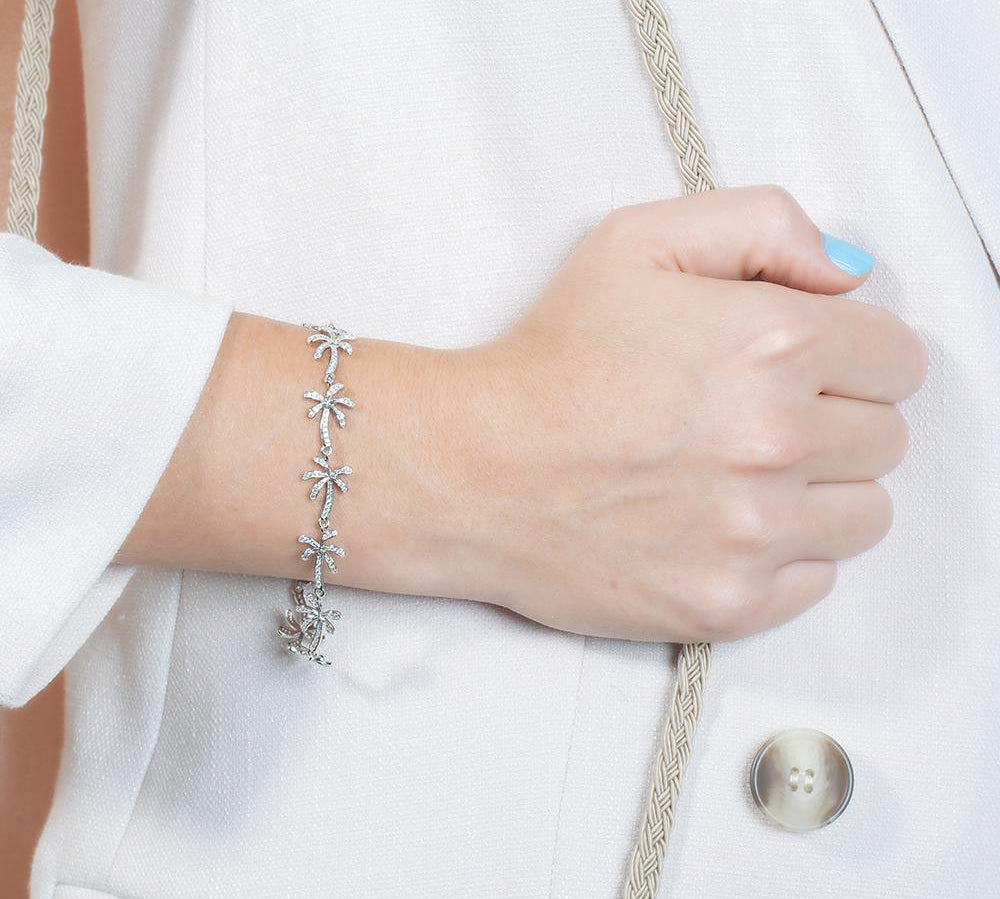 In this photo there is a model wearing a white gold plated palm tree bracelet with topaz gemstones.