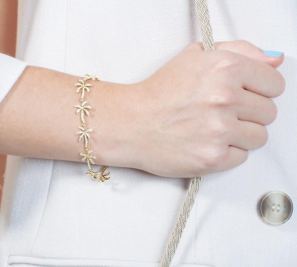 In this photo there is a model wearing a yellow gold plated palm tree bracelet with topaz gemstones.