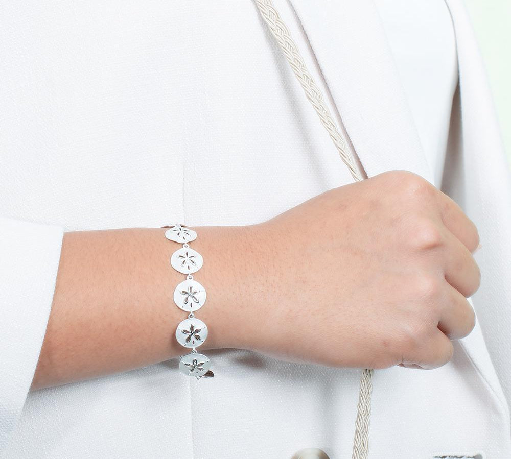 The picture shows a model wearing a white gold sand dollar bracelet