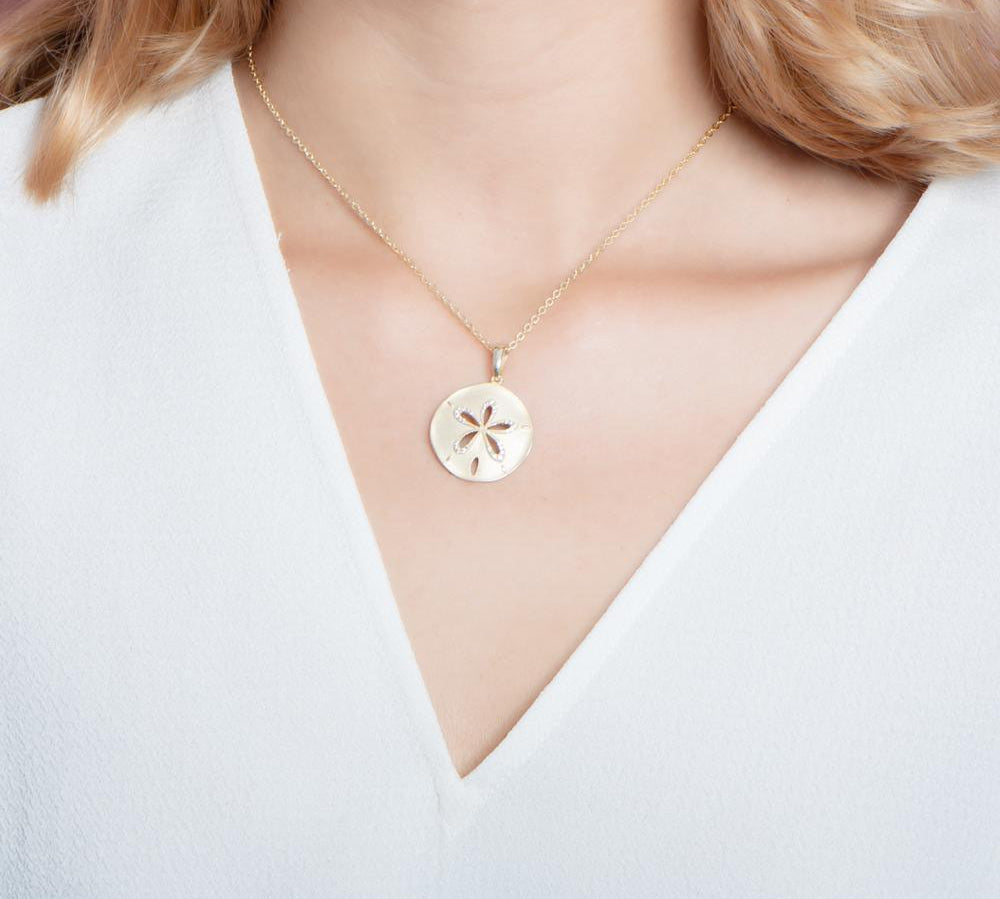The picture shows a model wearing a yellow gold sand dollar cut out pendant.
