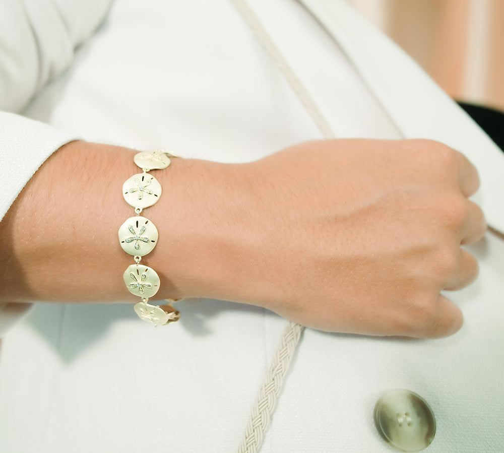 The picture shows a model wearing a yellow gold sand dollar bracelet with topaz.