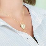 The picture shows a model wearing a yellow gold manta ray pendant with topaz.