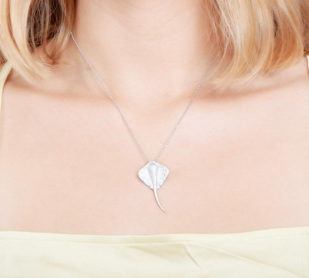  The picture shows a model wearing a white gold manta ray pendant with topaz.