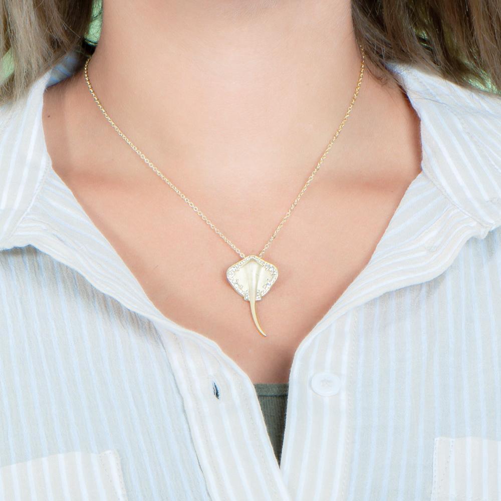 The picture shows a model wearing a yellow gold manta ray pendant with topaz.