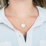 The picture shows a model wearing a yellow gold manta ray pendant with topaz.