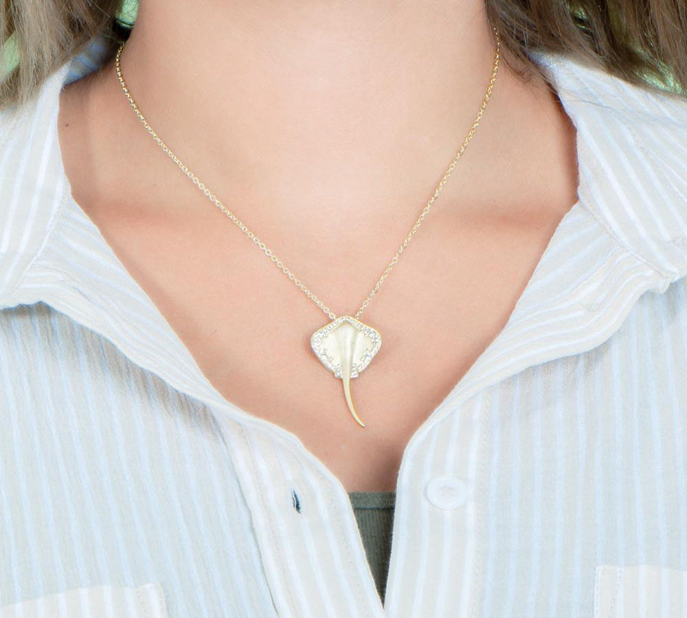 The picture shows a model wearing a yellow gold manta ray pendant with topaz.