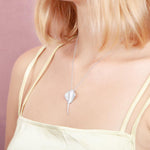  The picture shows a model wearing a white gold manta ray pendant with topaz.
