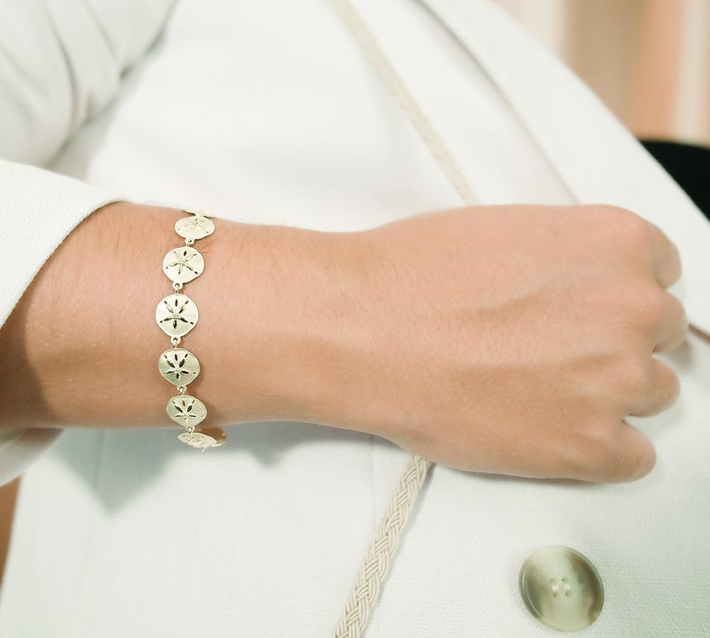 The picture shows a model wearing a yellow gold sand dollar bracelet with topaz
