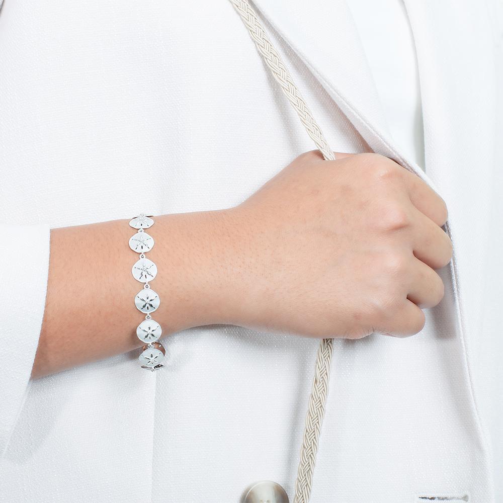 The picture shows a model wearing a white gold sand dollar bracelet with topaz