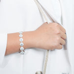 The picture shows a model wearing a white gold sand dollar bracelet with topaz