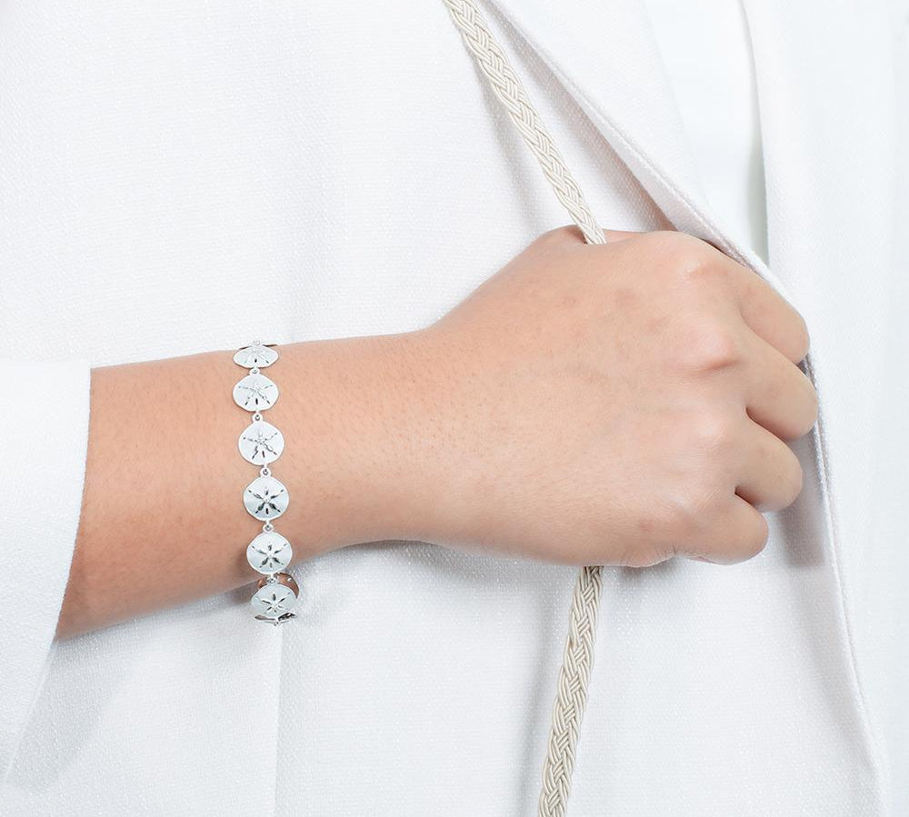 The picture shows a model wearing a white gold sand dollar bracelet with topaz