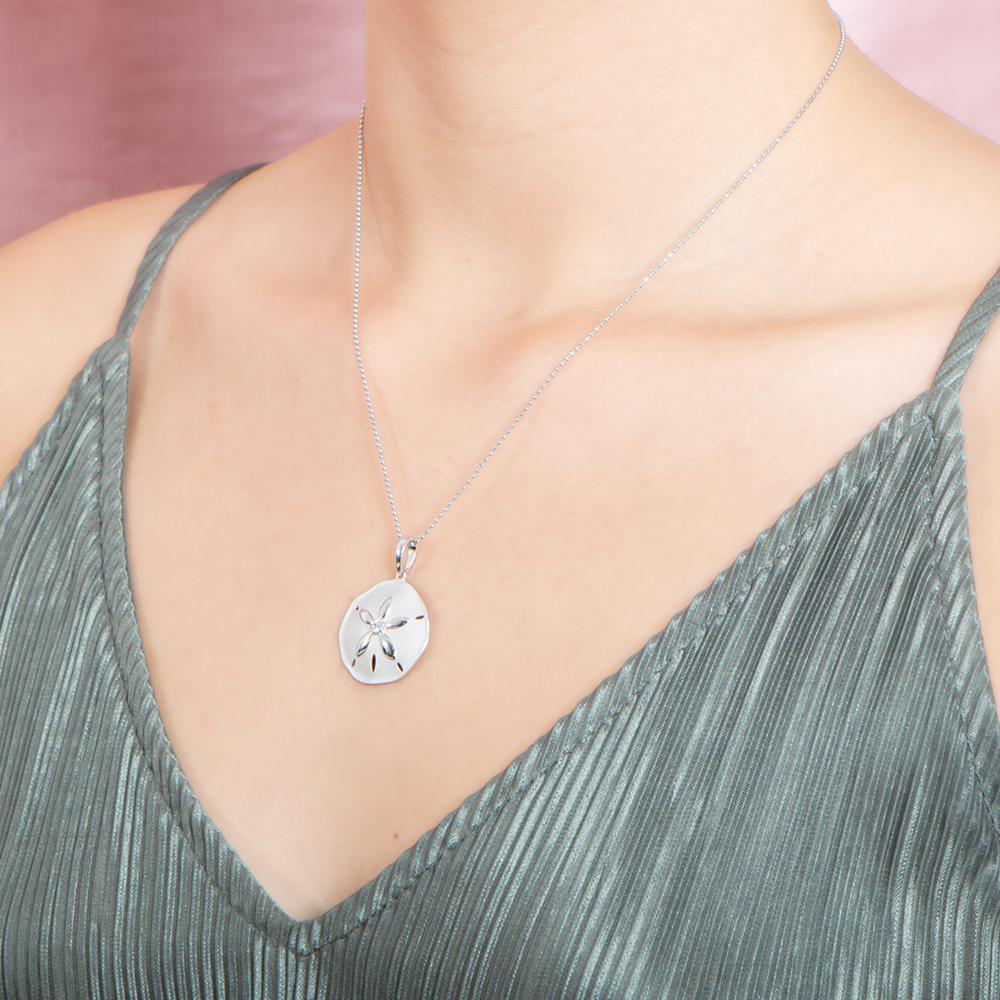 The picture shows a model wearing a white gold sand dollar pendant with topaz.
