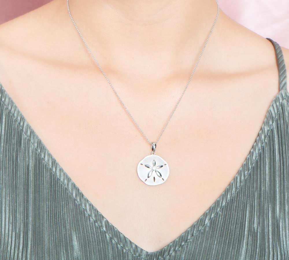 The picture shows a model wearing a white gold sand dollar pendant with topaz.