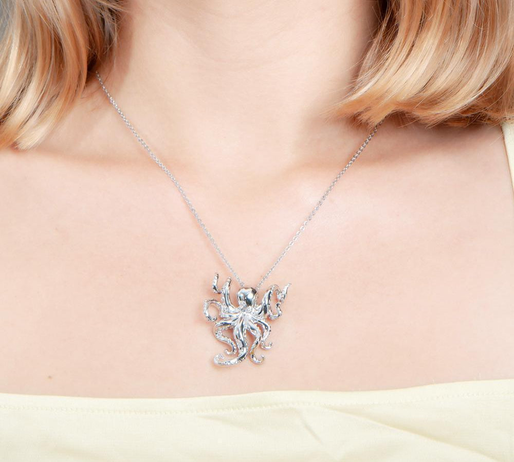 The picture shows a model wearing a 925 sterling silver swimming octopus pendant with topaz.