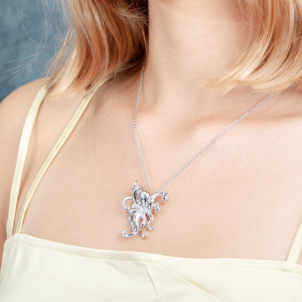 The picture shows a model wearing a 925 sterling silver swimming octopus pendant with topaz.