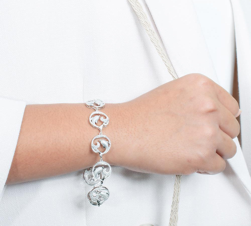 The picture shows a model wearing a white gold dolphin and wave bracelet with topaz.