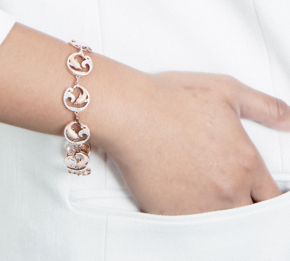 The picture shows a model wearing a rose gold dolphin and wave bracelet with topaz.