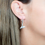 The picture shows a model wearing a 925 sterling silver whale tail earring with topaz.