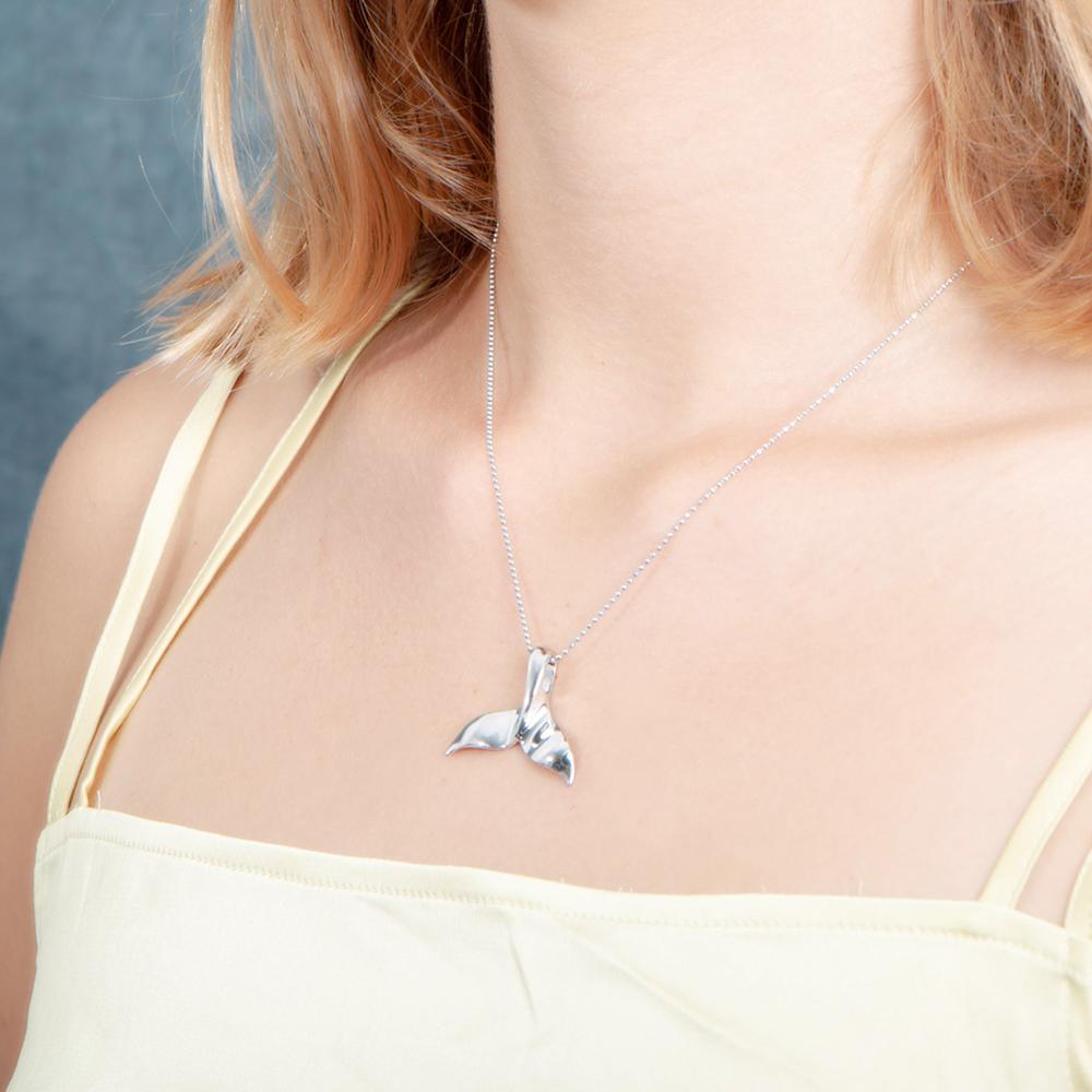 The picture shows a model wearing a 925 sterling silver whale tail pendant.